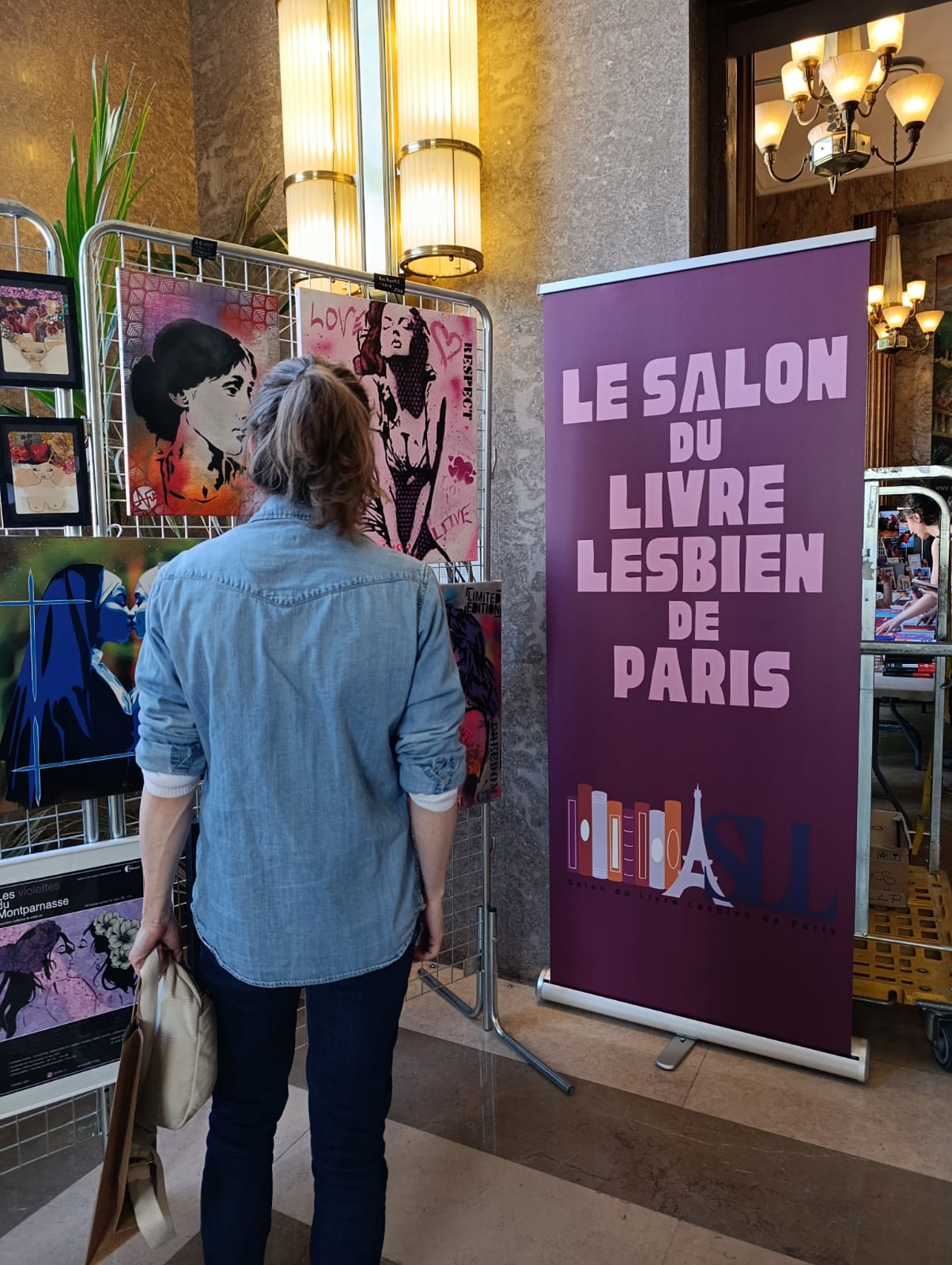 Photo du Salon du livre lesbien à Paris avec une bannière violette de l'événement